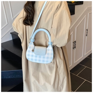 Detail of light blue gingham crossbody bag with silver logo and round handle on a model