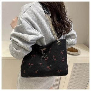 Close-up of black corduroy tote bag with cherry print and golden deer charm detail