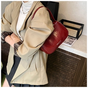 Detail of dark red glossy underarm bag with white Fashion & Bags text on leather surface
