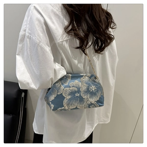 Blue silk shoulder bag with silver flower embroidery and gold chain shown on a model
