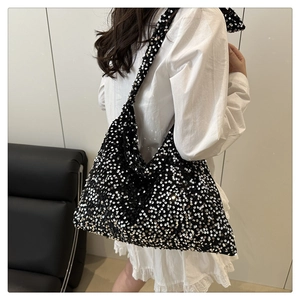 Close-up of black sequined tote bag with shimmering texture on a white shirt background
