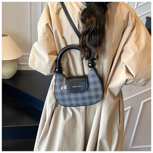 Detail of checkered crossbody bag with circular handle and metal ring charm decoration