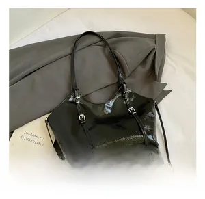 Detail of black glossy tote bag with silver metal buckles on a minimalist grey background