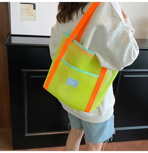 Detail of neon green mesh beach tote bag featuring orange straps and blue label on shoulder