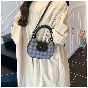 Detail of grey and black checkerboard crescent bag with metal hardware and leather strap