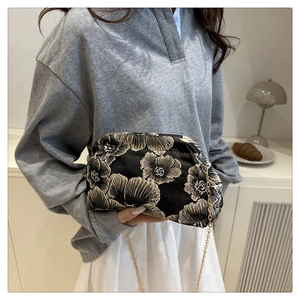 Detail of floral embroidery on a black cloud bag with luxury champagne gold chain strap