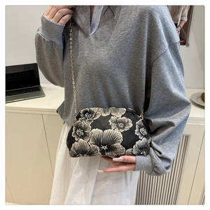 Detail of retro floral jacquard handbag with gold chain strap on grey outfit