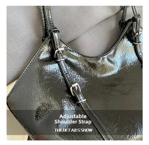 Detail of adjustable silver buckle strap on a black wrinkled faux leather tote bag