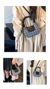 Detail of grey plaid crossbody bag with circular handle and silver logo hardware