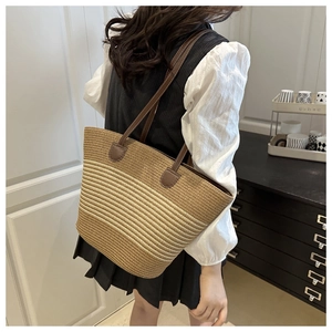 Détail d'un sac cabas en paille tressée avec anses en cuir marron et rayures