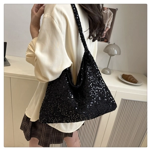 Detail of a black sequin tote bag showing the shimmering texture and wide shoulder strap