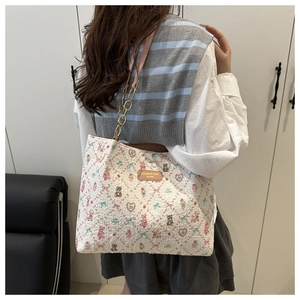 Détail du sac fourre-tout à motifs ours avec bandoulière chaîne porté par un modèle