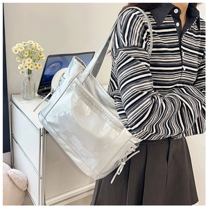 Détail du sac cabas argenté avec poche en PVC transparent et décoration de nœud latéral