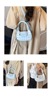 Detail of light blue gingham crossbody bag featuring a silver heart charm and curved handle