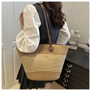 Détail du sac cabas en paille tissée avec anses en cuir marron et texture rayée