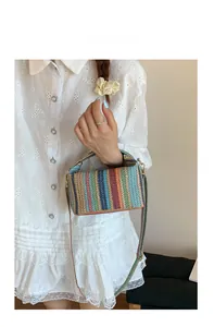 Détail d'un sac à main tissé à rayures colorées avec crochets en métal doré et bandoulière