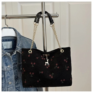 Detail view of black corduroy tote with red cherry embroidery and gold chain strap