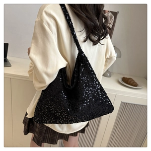 Close-up of a large black sequin tote bag on a model in a minimalist home setting