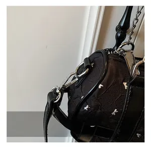 Gros plan du crochet métallique argenté et de la bandoulière d'un sac noir chic