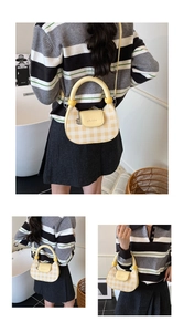 Detail of yellow checkered crossbody bag with unique spherical handle and refined flap