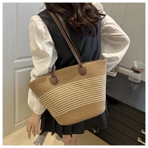 Détail d'un grand sac cabas tissé avec rayures bicolores et anses en cuir marron