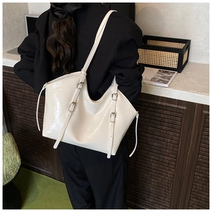 Close-up of cream white glossy patent leather tote bag with stylish buckle strap details