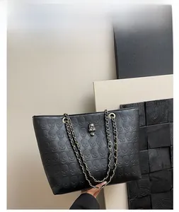 Detailed view of black tote bag with skull texture and gold chain strap handle