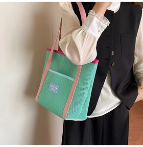 Close-up of green mesh tote bag with pink straps and brand label detail
