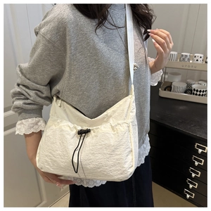 Detailed view of white nylon tote bag with drawstring pocket and wide shoulder strap