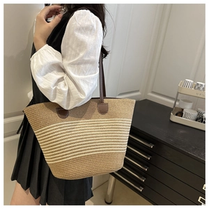 Détail du sac cabas en paille tissé avec rayures beiges et anses en cuir marron