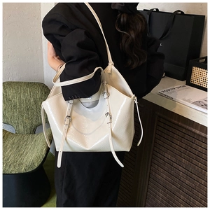 Detail view of cream tote bag with glossy finish and silver buckle on the shoulder strap