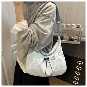 Detail of light blue nylon bag featuring adjustable black drawstring and wrinkled texture