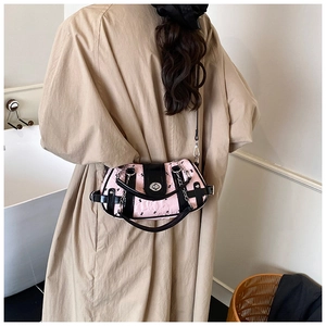 Détail du sac bandoulière rose et noir avec gaufrage papillon et chaîne en métal