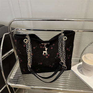 Black corduroy cherry print tote bag with metal chain strap and deer pendant detail