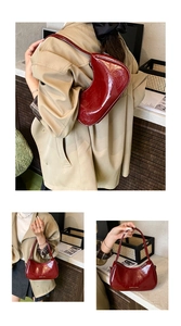Close-up of a glossy burgundy crescent shoulder bag with minimalist fashion text details