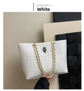 Close-up of white tote bag featuring skull embossed patterns and metal chain strap