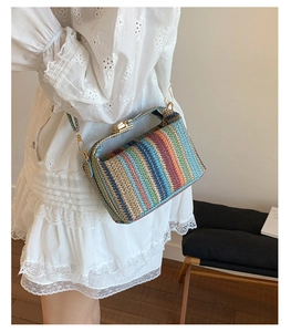 Détail du sac à bandoulière tissé arc-en-ciel avec fermoir doré sur robe blanche