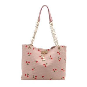 Pink corduroy tote bag with cherry print and golden chain shoulder strap in a frontal view