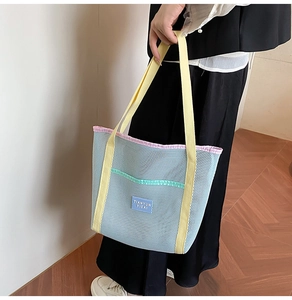 Detail of blue mesh beach tote bag with yellow straps and green zipper pocket