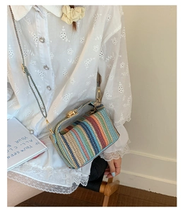 Détail du sac tissé aux rayures arc-en-ciel avec fermoir rotatif en métal doré et anse