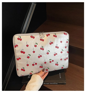 Close-up of silver laptop sleeve with cherry prints and dual metal zippers being held