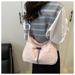 Pink nylon crossbody bag with drawstring closure shown on model in a casual setting