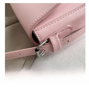 Close-up of pink leather underarm bag featuring silver buckle detail and reinforced stitching