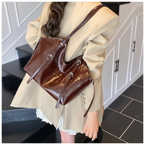 Close-up of a vintage dark brown glossy leather tote bag worn by a model on her shoulder