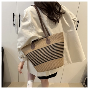 Détail du sac cabas en paille tressée avec rayures noires et bandoulières en cuir marron