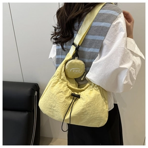 Detail of yellow nylon dumpling crossbody bag with adjustable drawstring and round pouch