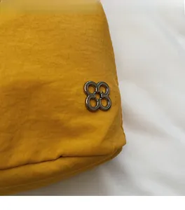 Dettaglio della borsa in tela giallo brillante con trama morbida e logo in metallo argento