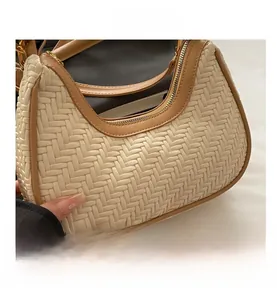 Close-up of cream woven hobo bag featuring tan leather trim and secure metal zipper detail