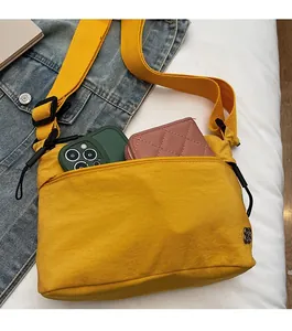 Dettaglio della tasca frontale con zip su una borsa a tracolla in nylon giallo per storage