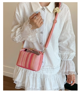 Détail du sac bandoulière tissé à rayures roses avec fermoir en métal et texture